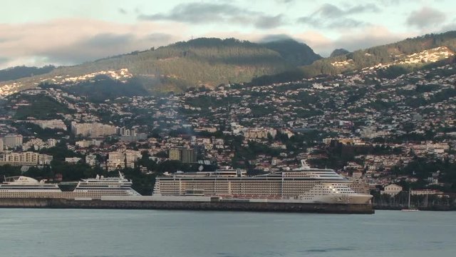 View from the bridge wing of a ship as it approaches the port of Funchal Madeira at dawn. Two large cruise ships are in port