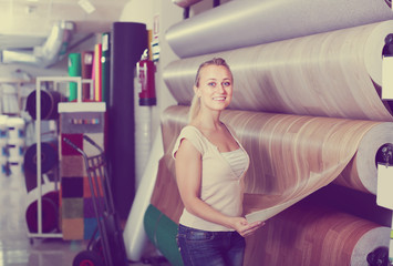 cheerful woman customer choosing linoleum flooring in hypermarke
