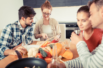 Young group of friends in kitchen preparing together vegetarian meal.Home party.