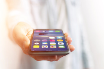 Hand holding black smartphone with operating system screen