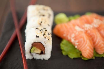 Uramaki and sashimi sushi served with chopsticks 
