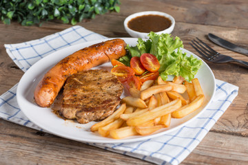 Roasted beef meat steak and sausage with french fries.