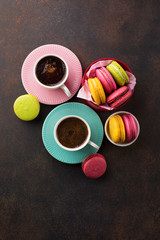 Obraz na płótnie Canvas Colorful macaroons. Sweet macarons and cups of coffee on retro dark background with copy space. Holiday time concept