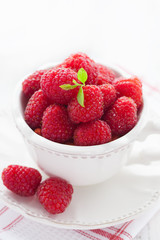 Cup of juicy raspberries on white wooden table, selective focus