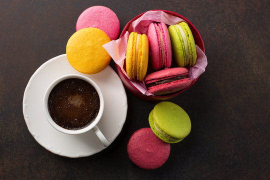 Colorful macaroons. Sweet macarons and cup of coffee on retro dark background with copy space. Top view. Holiday time concept