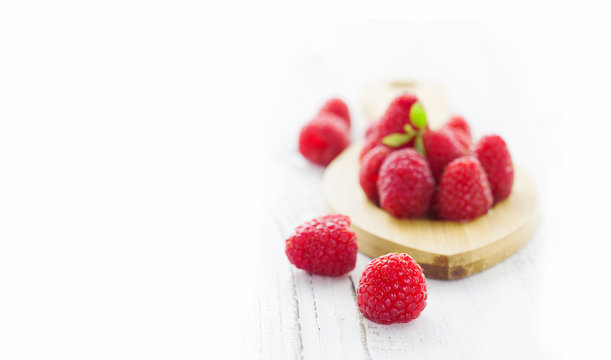 Juicy raspberries on white wooden table, selective focus