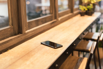 smart phone place on wooden table in coffee shop, Concept : Forg