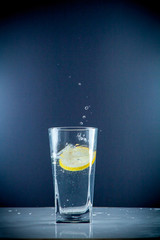 Glass glass of water with lemon on the isolated background. Mountain ineralnaya pure mountain water with gas bubbles and a lemon slice and spray tonic refreshing sports drink.
