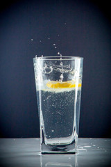Glass glass of water with lemon on the isolated background. Mountain ineralnaya pure mountain water with gas bubbles and a lemon slice and spray tonic refreshing sports drink.