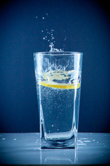 Glass glass of water with lemon on the isolated background. Mountain ineralnaya pure mountain water with gas bubbles and a lemon slice and spray tonic refreshing sports drink.
