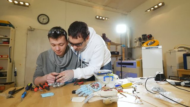 Two young engineers creating innovative cybernetic bionic arm. Hi-tech innovative technology. 4K.