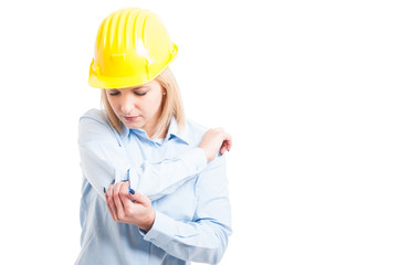 Female architect wearing helmet checking her elbow for injures