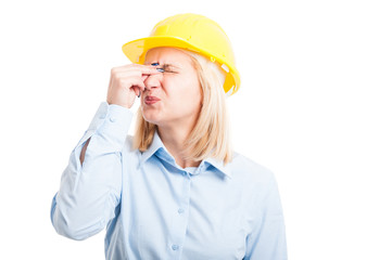 Female engineer wearing helmet making head ache gesture