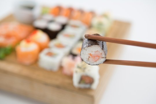 Maki sushi being held in wooden chopsticks