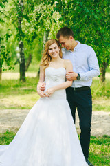 Just married loving hipster couple in wedding dress and suit on green field in a forest at sunset. happy bride and groom walking running and dancing in the summer meadow. Romantic Married young family