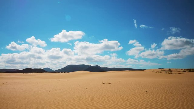 Timelapse shot of cloudscape rolling over desert and mountains. Scenic aerial view of blue sky on sunny day. Idyllic view of wave patterns on sand. 4K resolution.
