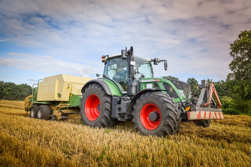 Fototapeta na wymiar Strohernte - Traktor mit Großballenpresse