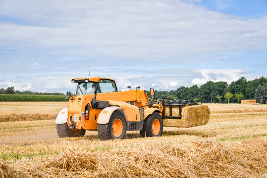 Strohernte - Teleskoplader sammelt Gro&szlig;ballen vom Feld