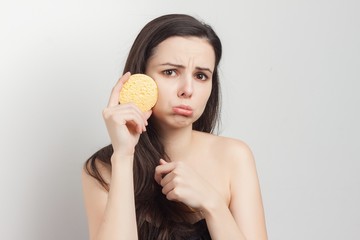 sad woman with pouting lips holds a sponge in her hand