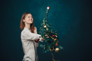 happy woman dresses up a Christmas tree, a holiday mood