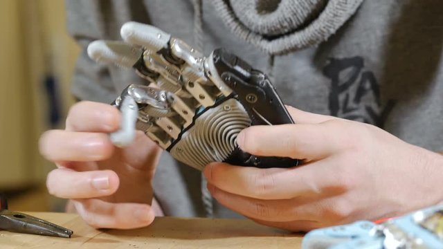 Man shows robotic bionic arm made on 3D printer. Dolly shot. 4K.