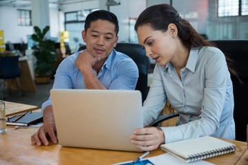 Business executives discussing over laptop