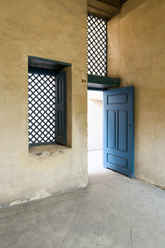 Blue vintage wooden window with interleaved wooden grid (mashrabiya) and blue wooden door with plaster yellow wall