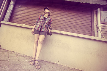 Woman in cap and with a camera standing near the wall