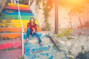 Woman in a multicolor sweater sitting on the rainbow stairs