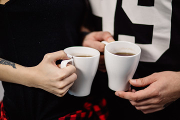 beautiful couple man and woman in black robes with white cups of tea are close-up