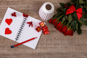 Red roses with hearts, gift boxes and vase. Valentines day concept. Red pencil with notebook. Love design. Wooden rustic board.
