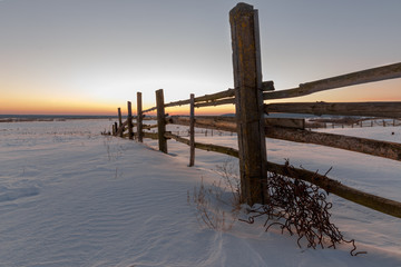 fence in a field in winter village at dawn