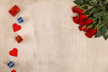 Red roses with hearts on wood background. Love design. Valentines day or 8 march concept. Fresh natural flowers with gift boxes. Wooden rustic board.