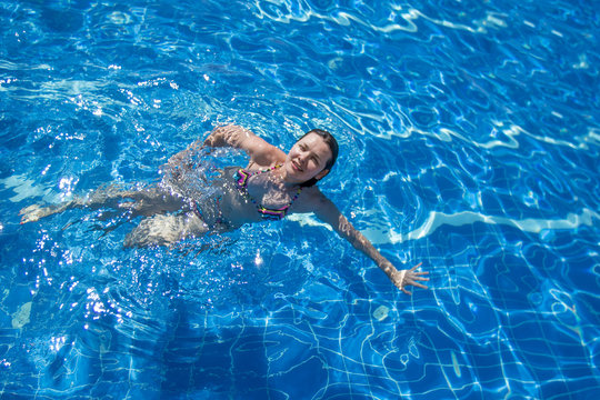 Brunette woman in a bikini  swimming in the pool