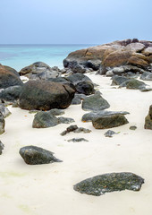 Rocks on white sand beach at lipe island