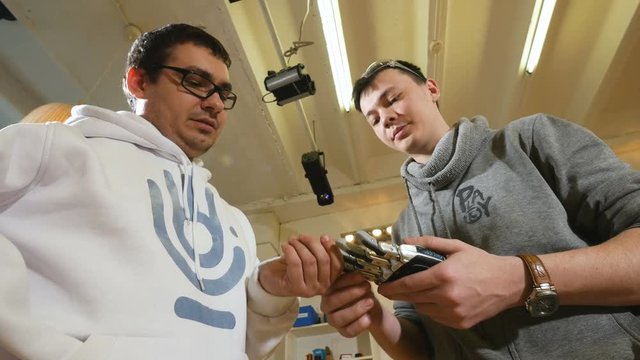 Engineers look at crafted robotic bionic arm made on 3D printer. 4K.