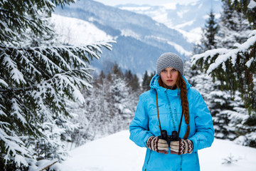 Fototapeta na wymiar Portrait of girl with binoculars in hand on the background of winter mountains