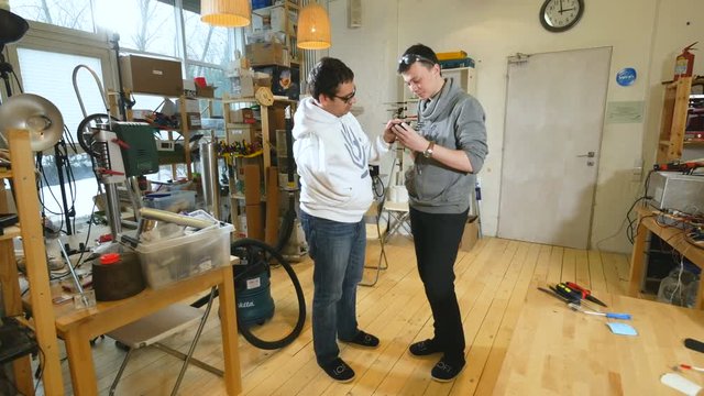 Engineers in lab discuss robotic bionic arm made on 3D printer. 4K.