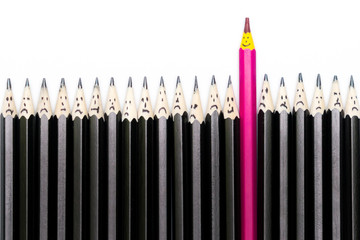 Pinker Buntstift mit Smiley spitzelt aus der Masse blasser Bleistifte heraus 