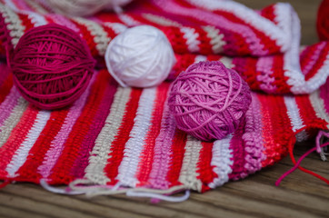 Fototapeta na wymiar small yarn balls on crocheted striped fabric in red colors