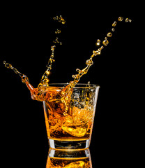 Glass of whiskey with splash on black background