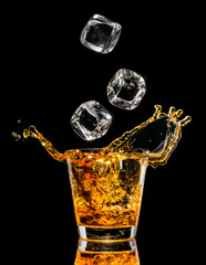 Glass of whiskey with splash on black background