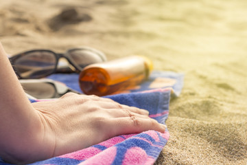 Woman on the beach with protection cream and sunglasses