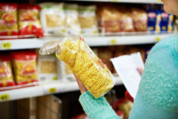 Woman with package pasta in shop