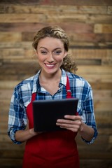 smiling waitress using tablet against wooden wall