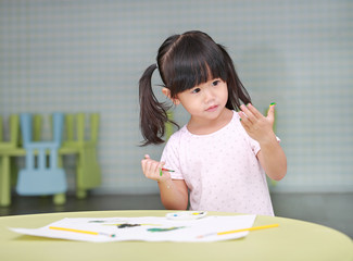 Cute asian child girl painting with paintbrush and water colors.