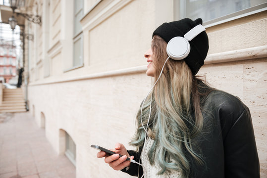 Side view of Young Woman listening music on the street