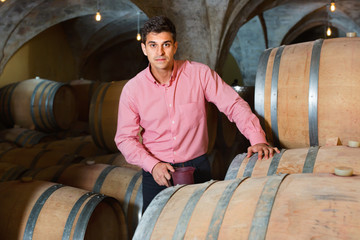Male customer tasting red wine from wooden barrels