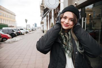 Fototapeta premium Woman in warm clothes listening music on the street