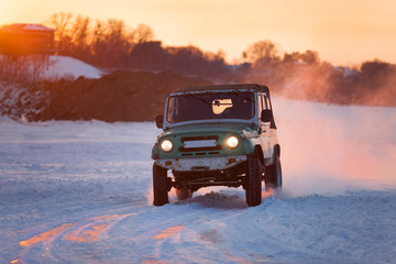 Russian UAZ 469 moving on ice of a frosn river at sunset